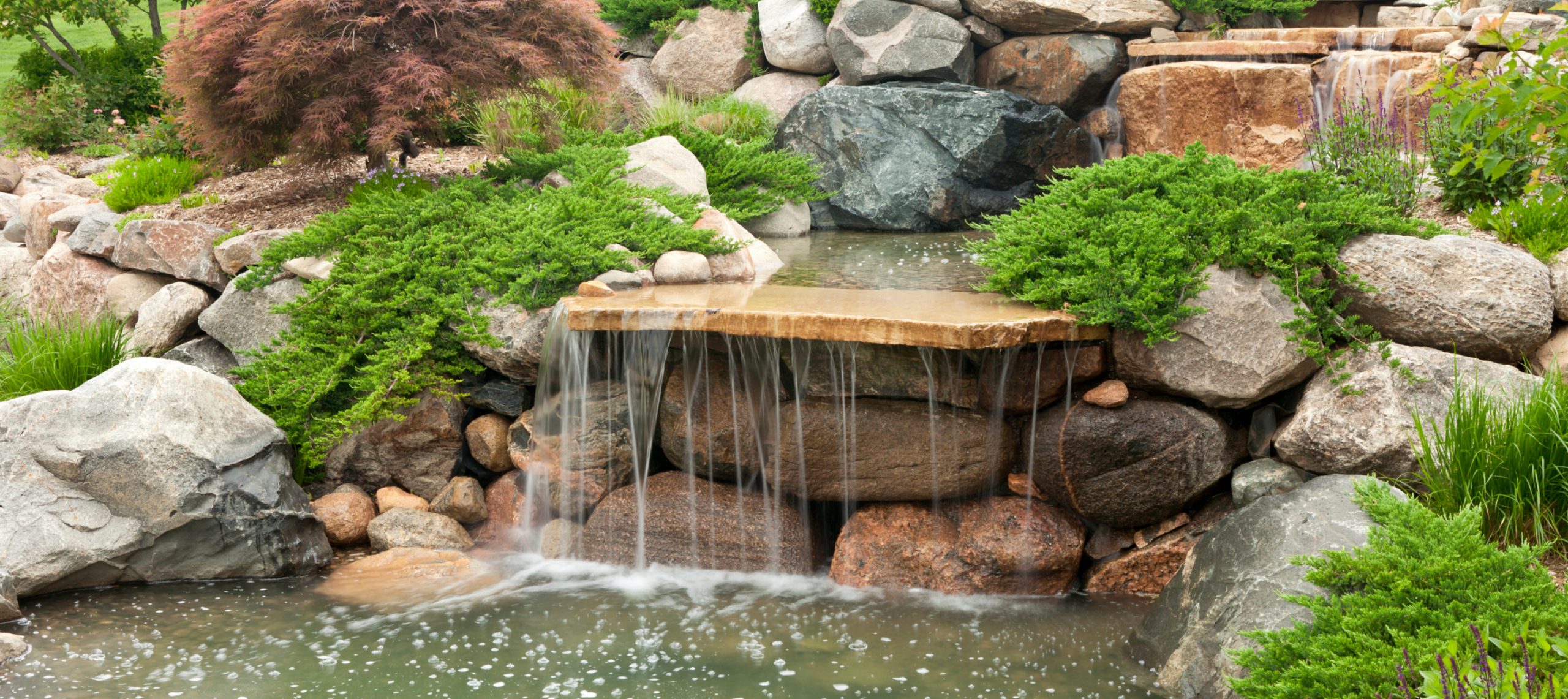 cascade bassin de jardin en rochers, terrasse en bois composite et mobilier  de jardin assorti