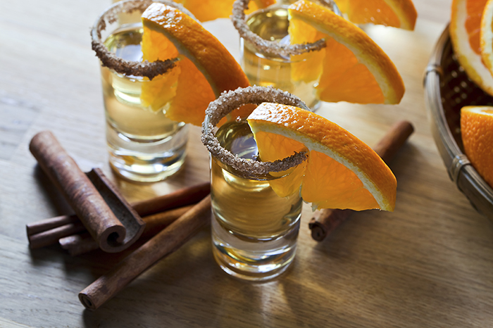 tequila with orange and cinnamon on a wooden table